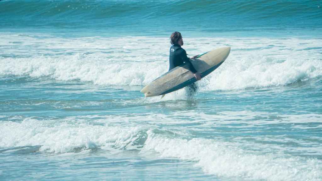 a surfer running towards the sea